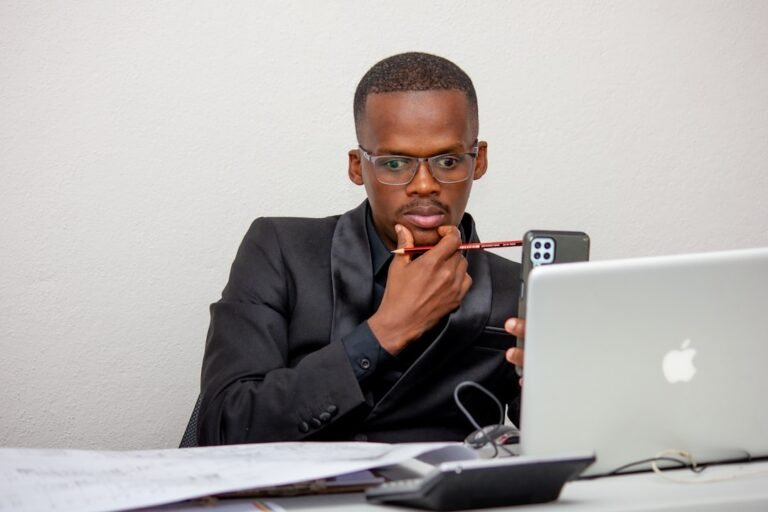 Um Homem Sentado Em Uma Mesa Com Um Laptop E Um Telefone 0GcTK4dbnxA